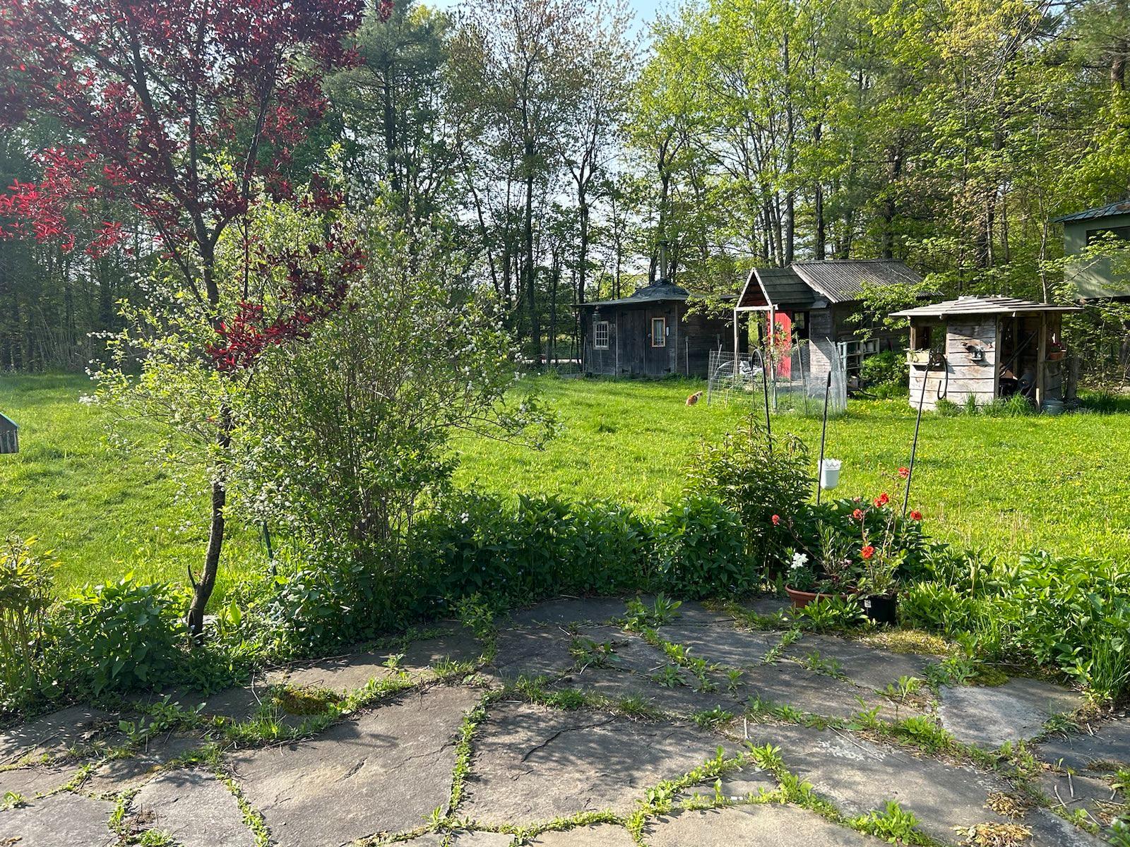 Patio view to the south; across the front yard there are views of the valley. Center background (with windows and chimney) is Rocky Hill Forge, our son&rsquo;s blacksmith forge.