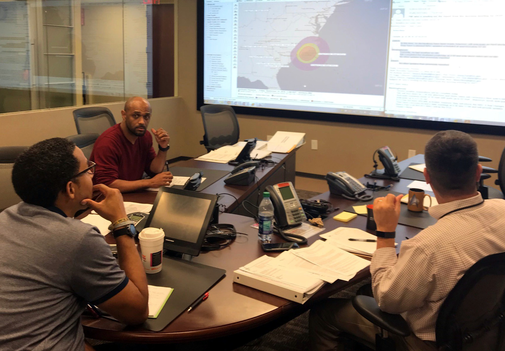 A photograph of a team of three men viewing a storm map